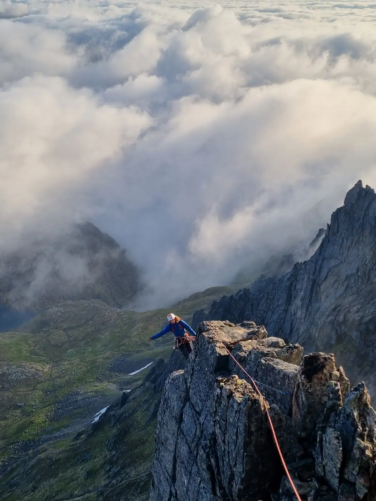Klatrer på luftig fjellrygg over skyene